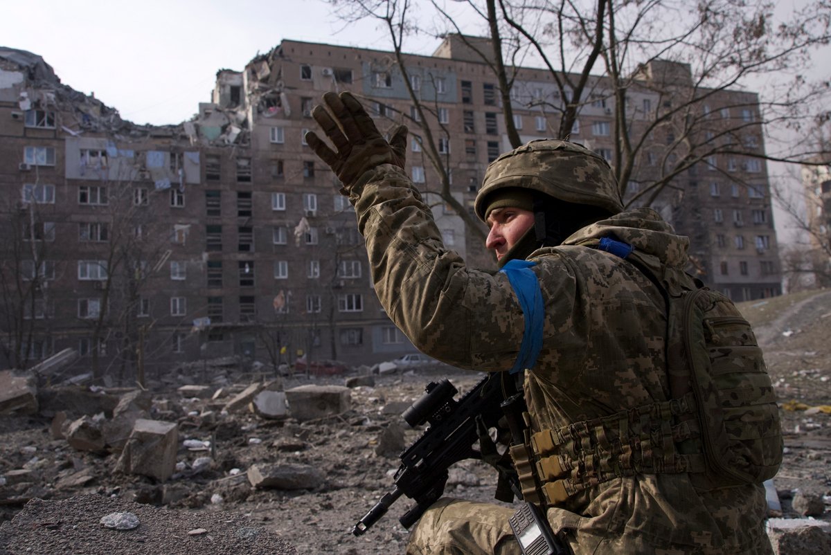 Украинский военнослужащий на фоне разрушенного жилого дома в Мариуполе, 12 марта 2022 года. Фото: Evgeniy Maloletka / AP Photo / Scanpix / LETA