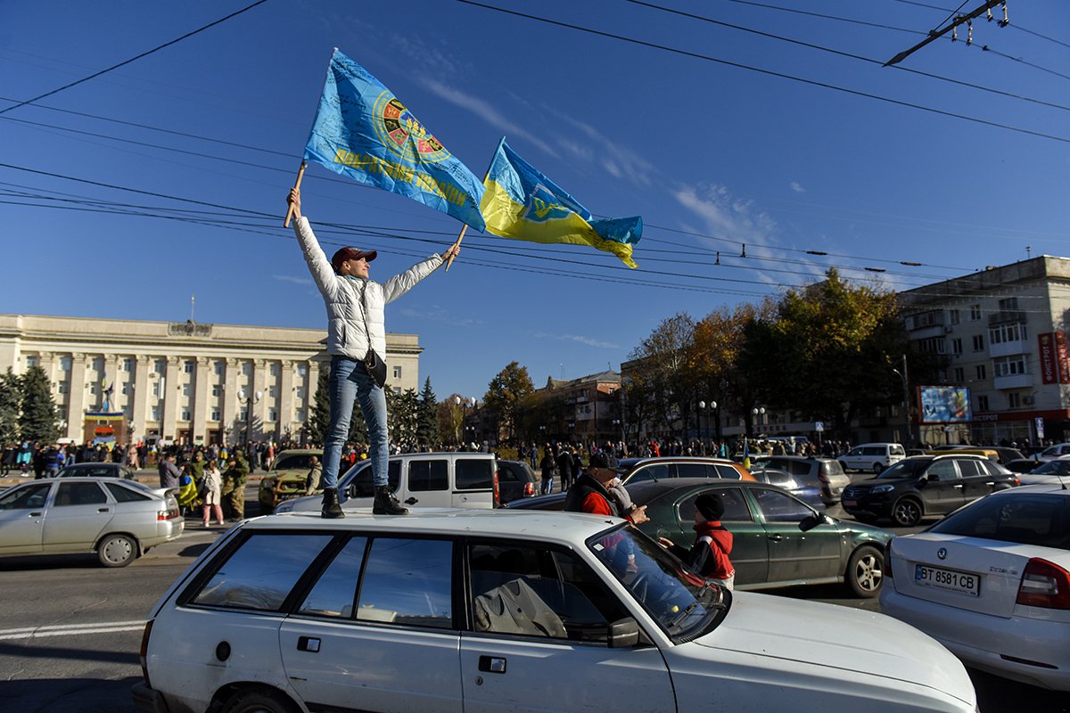 Люди машут украинскими флагами после визита Президента Зеленского в освобожденный Херсон, Украина, 14 ноября 2022 года. Фото: Олег Петрасюк / EPA-EFE