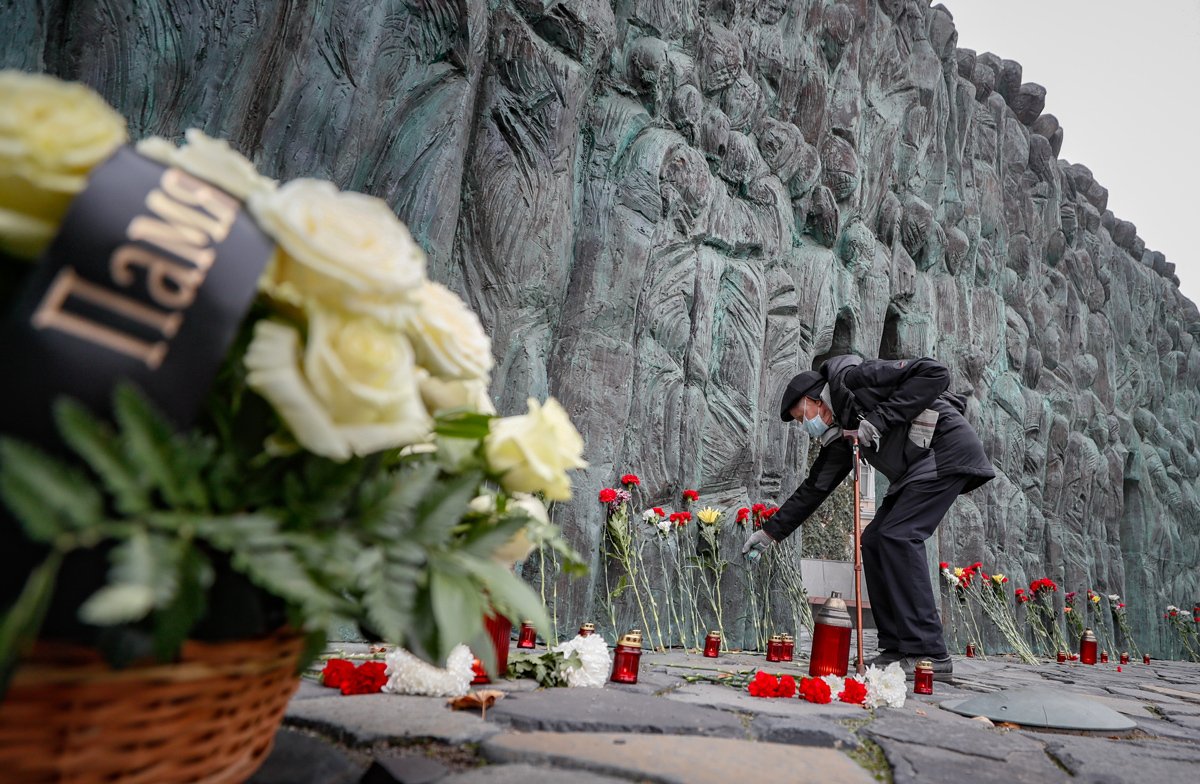 Мужчина возлагает цветы к монументу в память жертв политических репрессий в Москве, 30 октября 2022 года. Фото: Юрий Кочетков / EPA-EFE