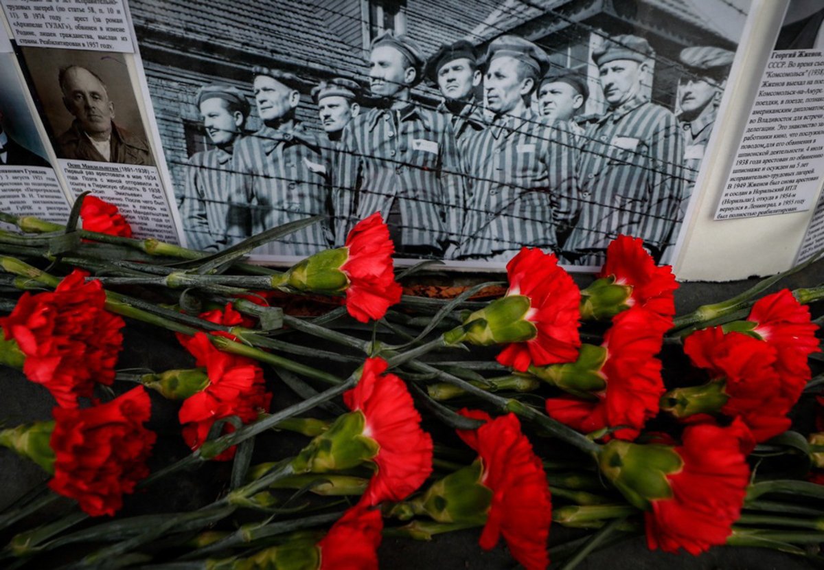 Цветы перед фотографией заключенных во время мемориальной акции в память о жертвах советских репрессивных лагерей ГУЛАГа. Фото: Юрий Кочетков / EPA-EFE