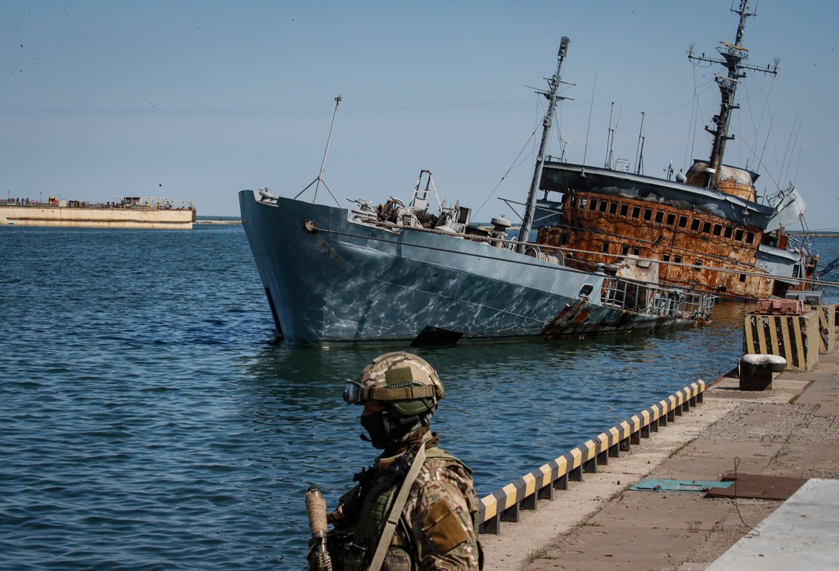 Российский военный на фоне затонувшего корабля в мариупольском грузовом порту, 29 апреля 2022 года. Фото: Сергей Ильницкий / EPA