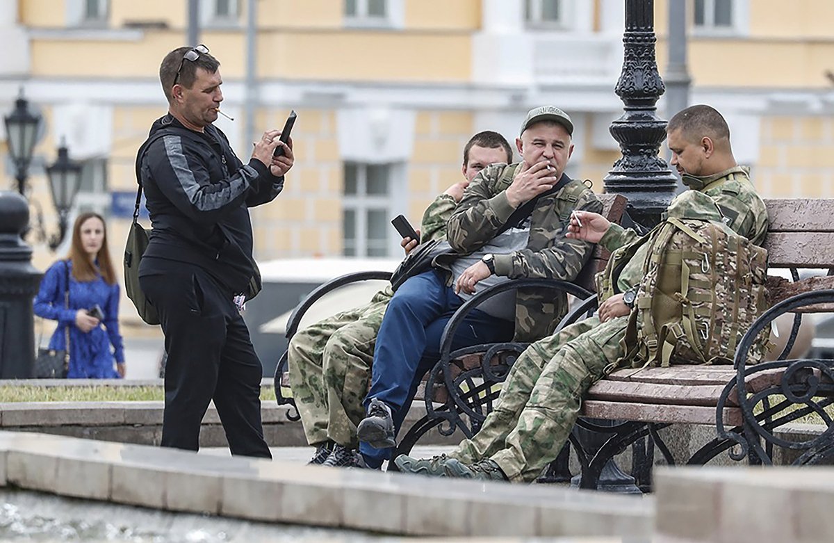 Мужчины, одетые в военную форму, отдыхают на скамейке в центре Москвы, Россия, 27 июня 2023 года. Фото: Максим Шипенков / EPA-EFE