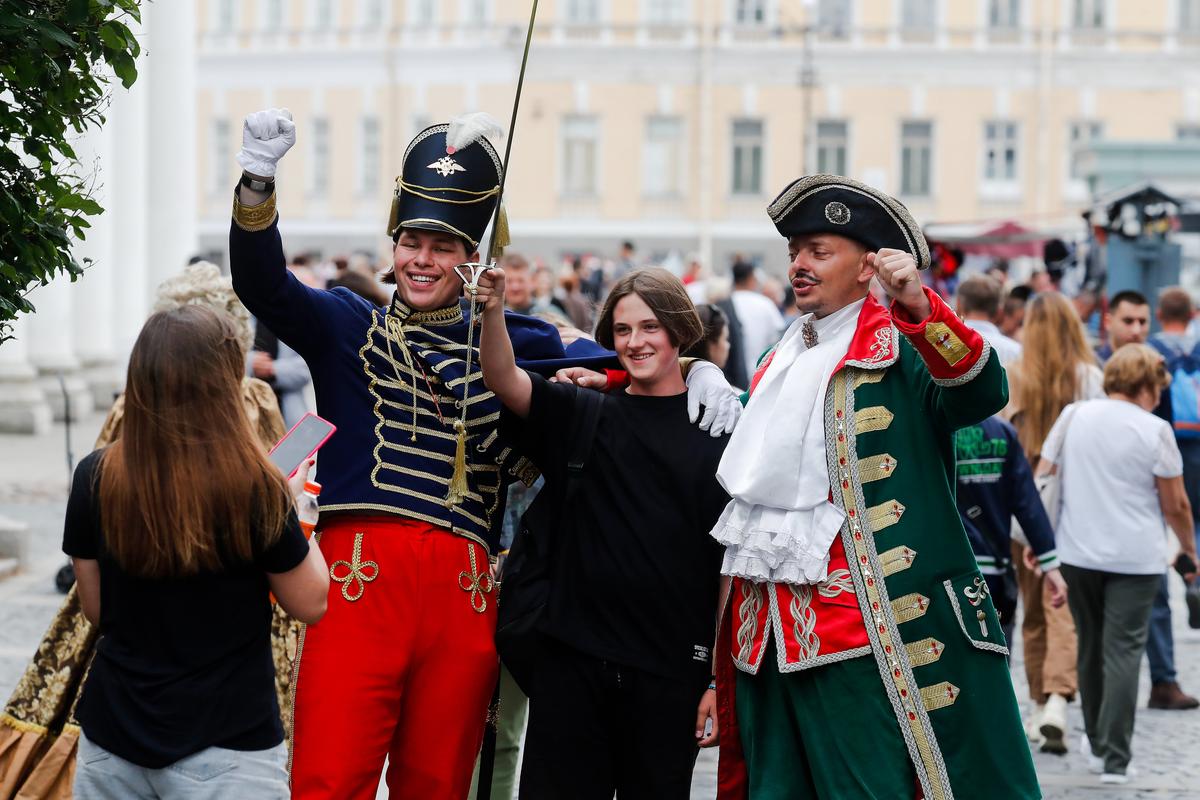 Люди позируют для фотографий с уличными актерами в центре Санкт-Петербурга, Россия, 13 июля 2023 года. Фото: Анатолий Мальцев / EPA-EFE